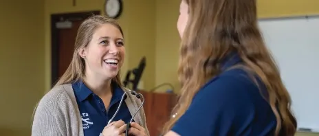 A woman conducting an evaluation on another woman during a physical therapy training.